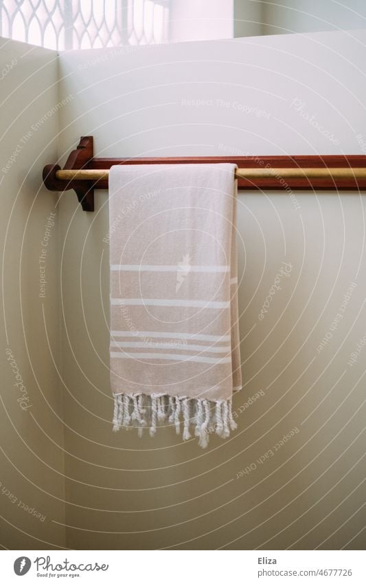 Handtuch an Handtuchhalterung an weißer Wand im Badezimmer Hammamtuch Stange Badetuch orientalisch gestreift hell Spa