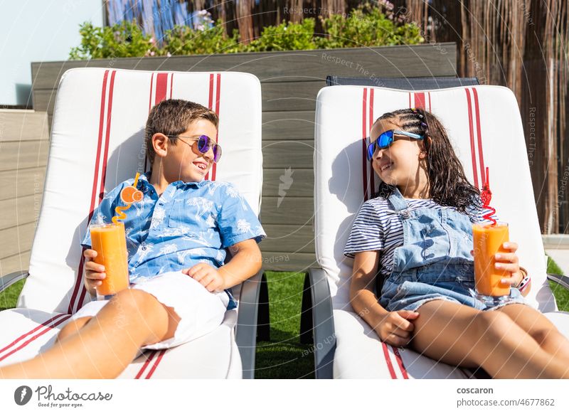 Zwei Kinder trinken Orangensaft in einer Hängematte Junge Windstille Kaukasier Kindheit Zitrusfrüchte Nahaufnahme Tag genießen frisch Garten Mädchen Glas Brille