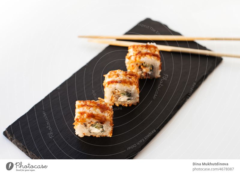 Sushi Japan Essen auf schwarzem Stein Platte im Sushi-Restaurant oder zum Mitnehmen mit Stäbchen auf weiß. Gourmet köstliche Sushi japanisches Essen mit Essstäbchen frisch im Restaurant oder Takeout Lieferung.