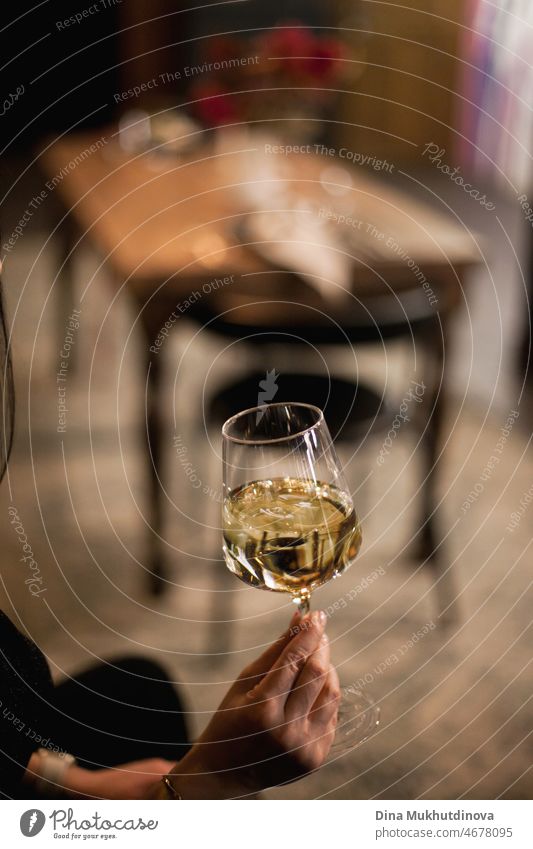 Die Hand hält ein Glas Weißwein in einer Bar oder einem Restaurant. Trinken von Wein und feiern besonderen Anlass oder Urlaub. Feier Hintergrund Alkohol