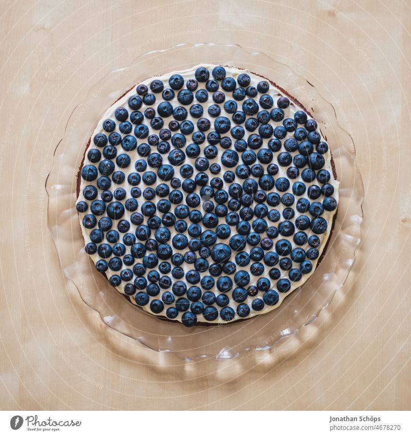 Blaubeeren auf der Sahnetorte auf Tortenplatte aus Glas Heidelbeeren Obst Beeren blau gesund Antioxidantien Vitamine Lebensmittel lecker Saisonal frisch Frucht