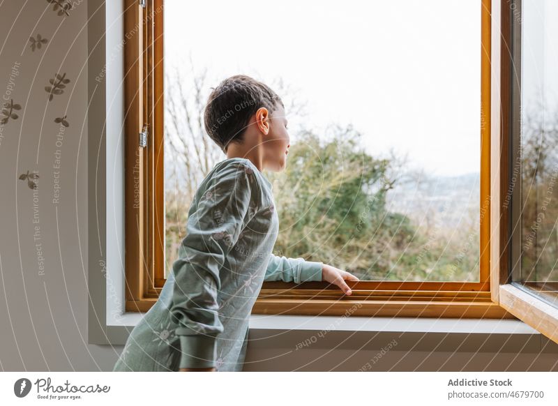 Junge im Pyjama schaut aus dem Fenster Kind beobachten Interesse neugierig Kindheit heimisch Morgen Appartement bezaubernd flach niedlich heimwärts wohnbedingt