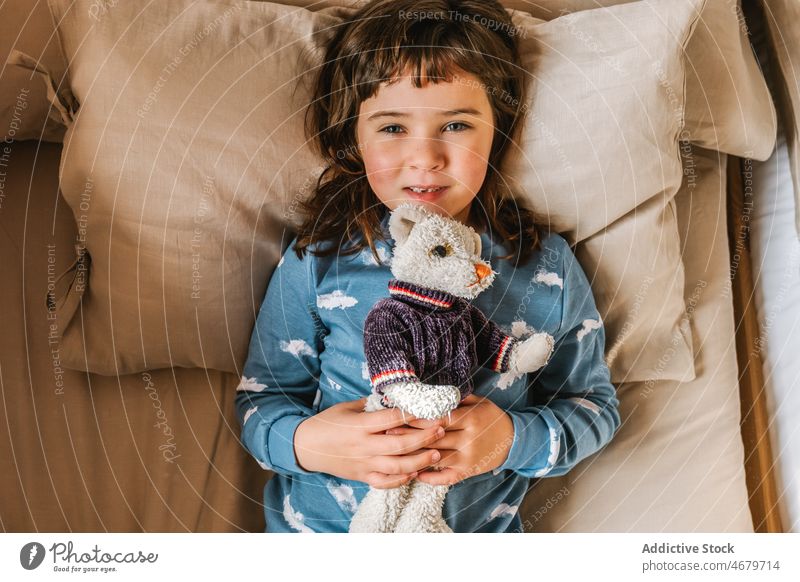 Niedliches Mädchen mit Spielzeug auf dem Bett Kind Kindheit Schlafzimmer Morgen heimisch Schlafenszeit Pyjama Bär gemütlich Appartement bezaubernd flach