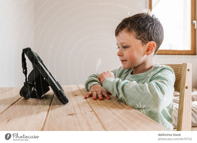 Niedlicher Junge im Pyjama schaut Video auf Tablet Kind Kindheit Tablette Karikatur Zeitvertreib Morgen heimisch Raum Appartement bezaubernd flach niedlich