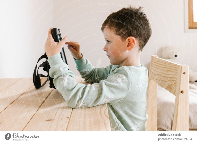 Niedlicher Junge im Pyjama schaut Video auf Tablet Kind Kindheit Tablette Karikatur Zeitvertreib Morgen heimisch Raum Appartement bezaubernd flach niedlich