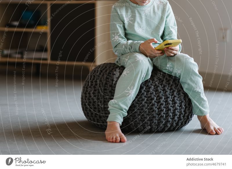Anonymer Junge im Pyjama, der auf seinem Smartphone spielt Kind Kindheit Videospiel spielen Zeitvertreib Morgen heimisch Raum Appartement bezaubernd Barfuß