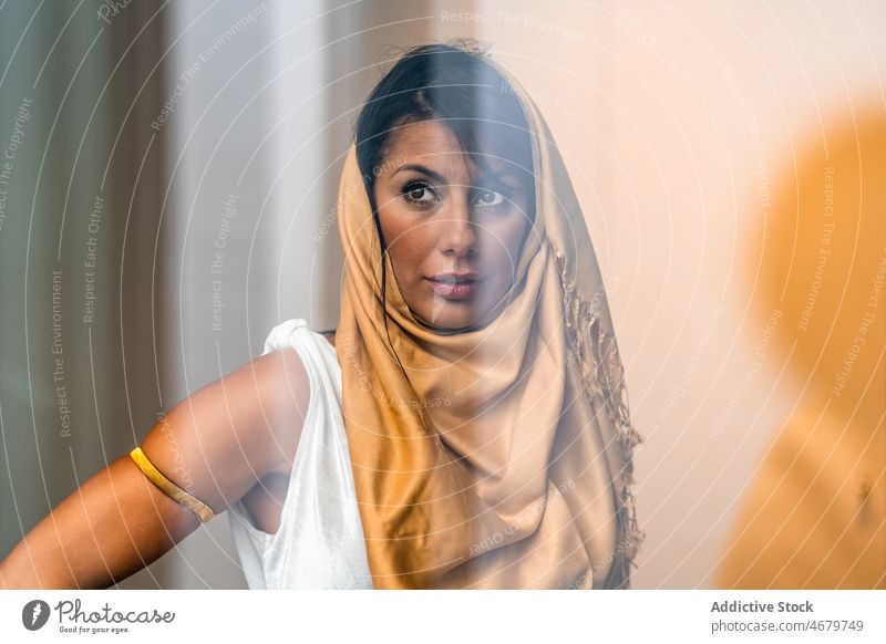 Durch das Glas einer muslimischen Frau am Fenster Vorschein traditionell authentisch Kultur Hijab feminin Stil Raum ethnisch Kopfbedeckung Kopfschmuck heimwärts