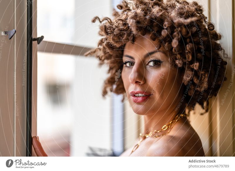 Elegante Frau steht am Fenster heimwärts elegant fettarm Stil tagsüber Porträt Erwachsener ethnisch Kurze Haare Halskette Angebot Sonnenlicht Accessoire golden