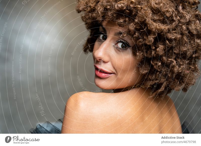 Positive Frau mit lockigem Haar schaut in die Kamera Stil elegant Make-up krause Haare Vorschein Porträt Model ethnisch Erwachsener Kurze Haare Individualität