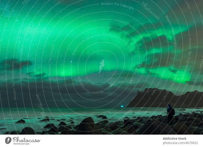 Anonyme Person bewundert sternenklare Nacht mit Polarlicht vom felsigen Meeresufer aus Aurora MEER Natur polar Reisender bewundern Tourismus Meereslandschaft