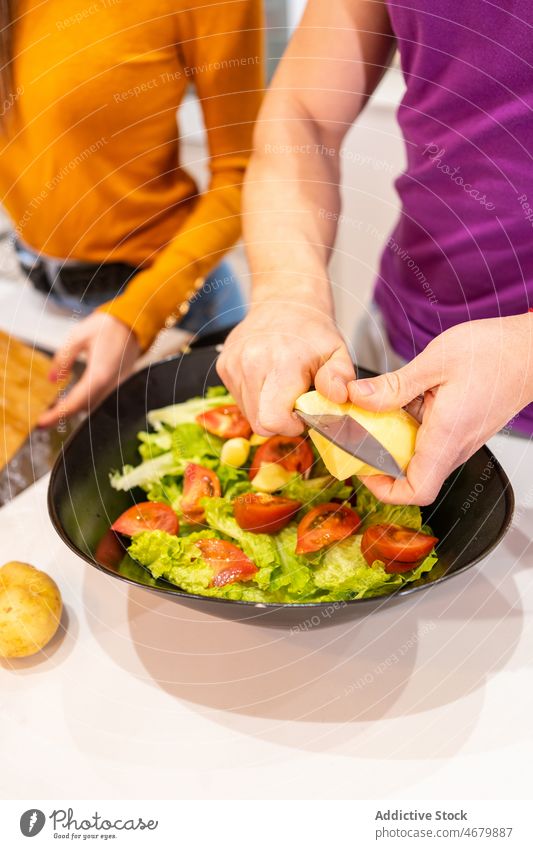 Anonymer Mann macht Salat in der Nähe einer gesichtslosen Frau Paar Küche Koch Salatbeilage Lebensmittel kulinarisch selbstgemacht Rezept Käse Bestandteil