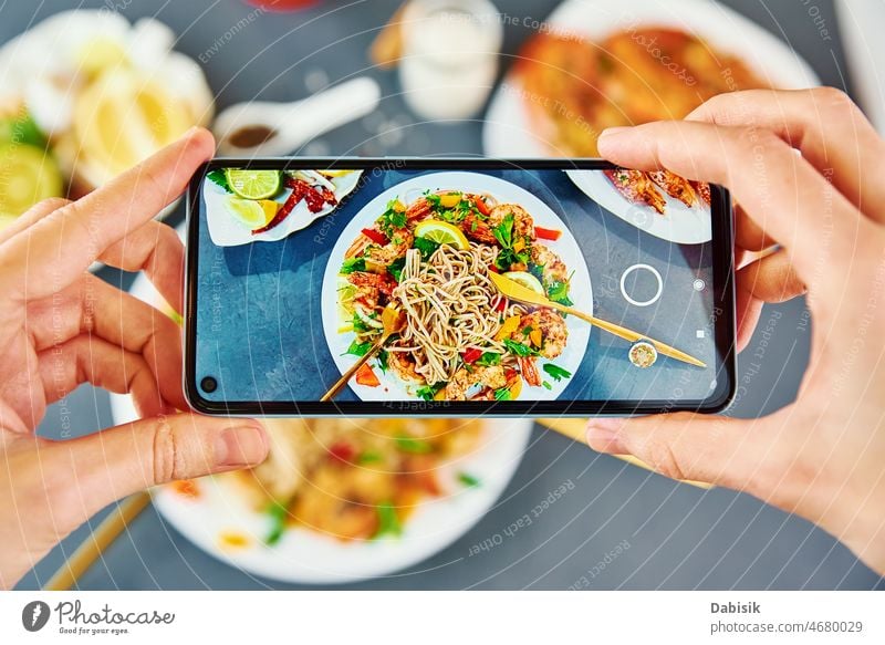 Foto von gebratenen Nudeln mit dem Smartphone für soziale Medien machen Lebensmittel Fotografie Wok soba asiatisch Telefon Ernährung Küche Mobile pov Restaurant