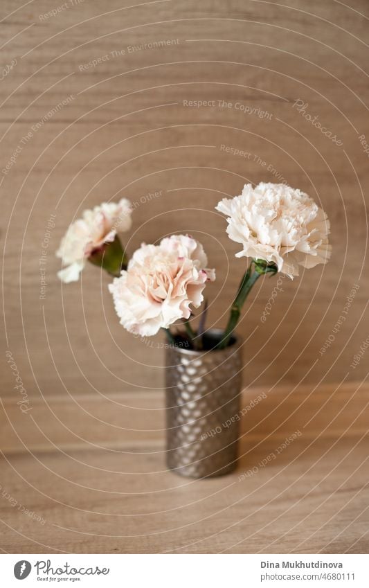 Drei Pfirsich Farbe Nelken Bouquet in einer kleinen Vase auf Holztisch isoliert. Floral vertikale Kulisse. Romantische Überraschung für einen Geburtstag oder eine Hochzeit.