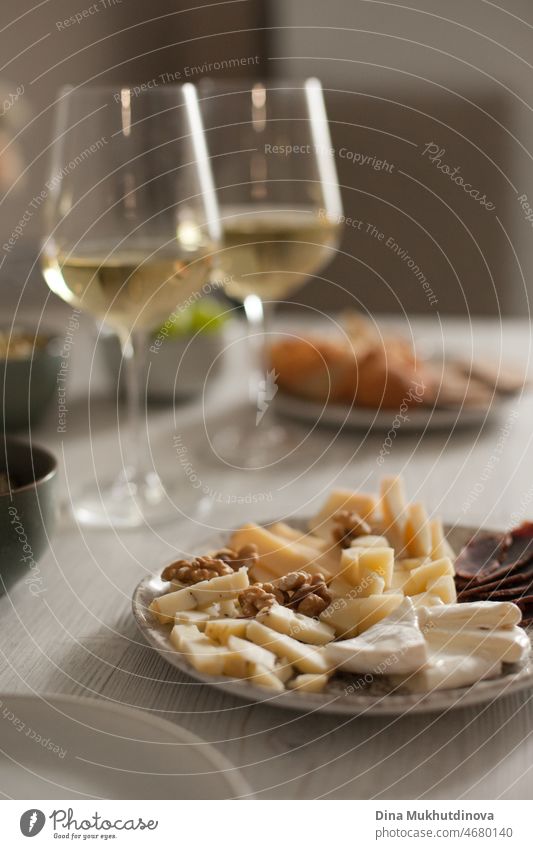 Leckere Gourmet-Käseplatte und zwei Weißweingläser auf dem Tisch. Käsesammlung oder verschiedene Sorten. Käse und Aufschnitt Auswahl. Vorspeisen und Wein romantisches Date-Dinner.
