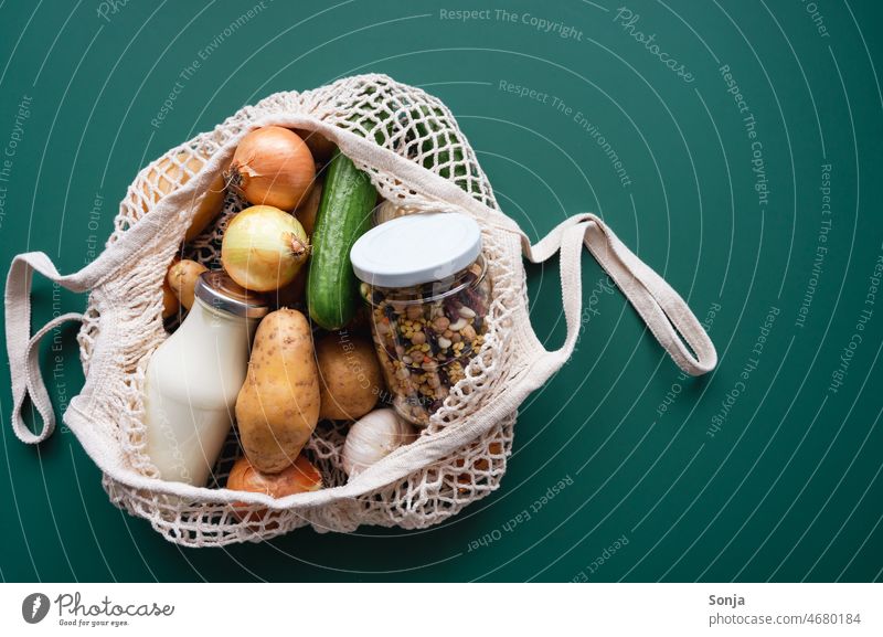 Ein Einkaufsnetz gefüllt mit frischen Gemüse, einer Milchflasche und Hülsenfrüchte im Einmachglas roh Einkaufen Draufsicht Vegetarische Ernährung Gesundheit