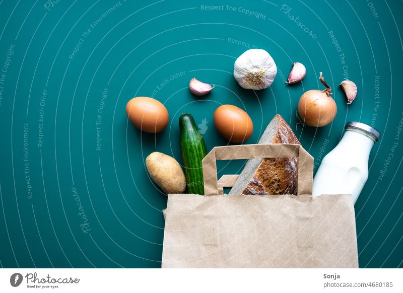 Eine Papier Einkaufstasche mit Gemüse, Brot, Eier und einer Milchflasche auf einem grünen Hintergrund frisch eier Einkaufen von Lebensmitteln Gesundheit lecker