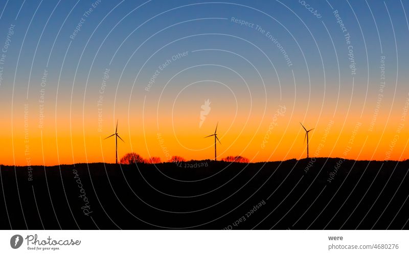 Silhouetten von drei Windturbinen gegen einen prächtigen farbigen Abendhimmel CO²-Neutralität Elektromobilität klimaneutral Klimaziele wolkenlos farbenfroh
