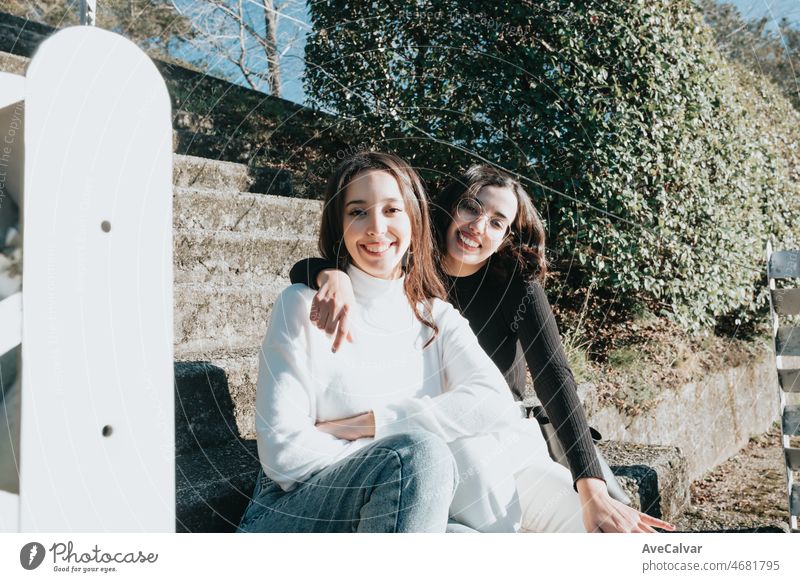 Porträt eines Paares von jungen Studenten Frau umarmt einander außerhalb des Campus sitzen auf Treppen und lächelnd in die Kamera. Glückliche Haltung jung und dynamisch Konzept. Trendy und modernen Stil