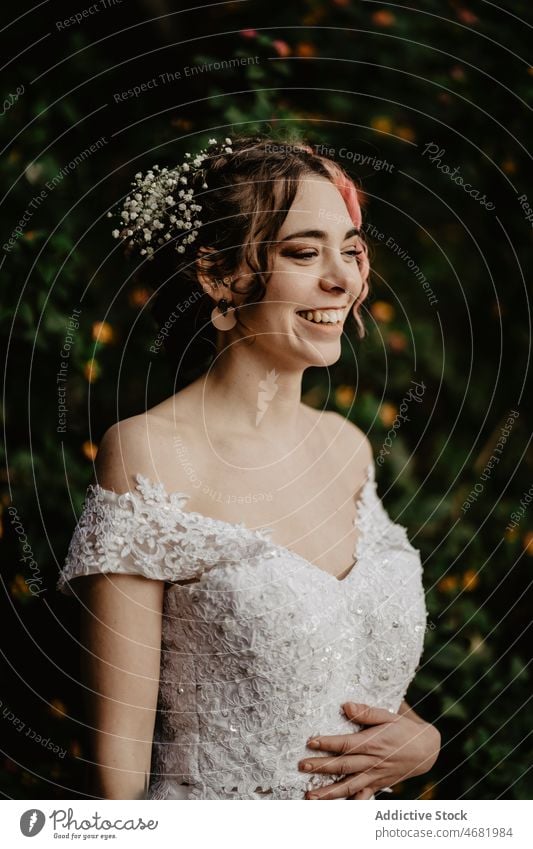 Junge fröhliche Braut in der Nähe von Busch im Garten Frau Hochzeit Lächeln Strauch Glück Festakt Tradition romantisch feiern Freude Kleid Stein heiter Buchse