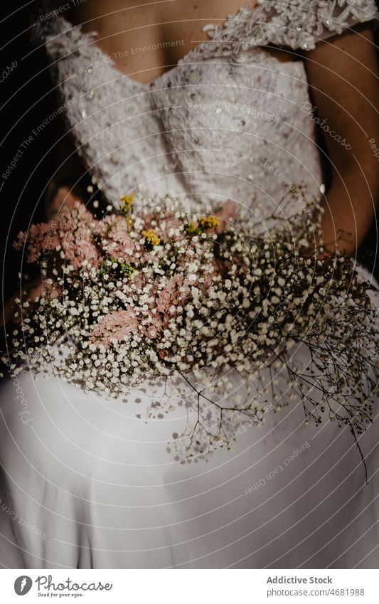 Crop Verlobte mit Brautstrauß Frau Blumenstrauß Hochzeit elegant dunkel Stil weißes Kleid romantisch Jungvermählter sitzen hochzeitlich Heirat Veranstaltung