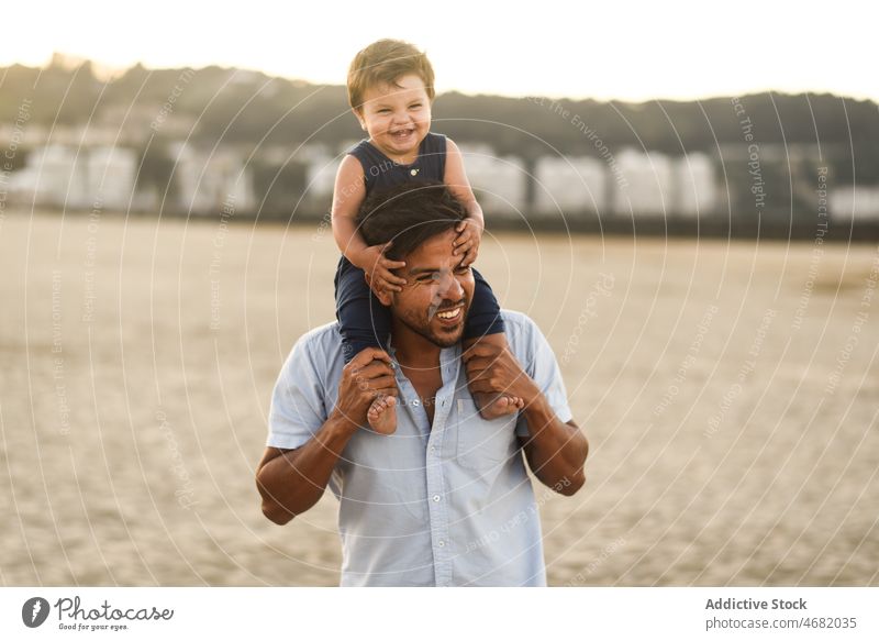 Glücklicher lateinamerikanischer Mann mit Junge am Strand Vater Sohn Vaterschaft Kind spielerisch Küste auf den Schultern Kindheit Erholung Lachen Sand Sommer