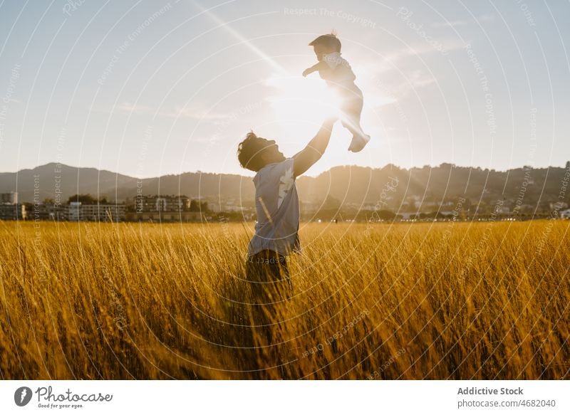 Anonymer Mann verbringt Zeit mit seinem kleinen Sohn im gelben Feld Papa Vater Kleinkind Kind Spaß haben werfen Landschaft Wiese Gras männlich ländlich Eltern