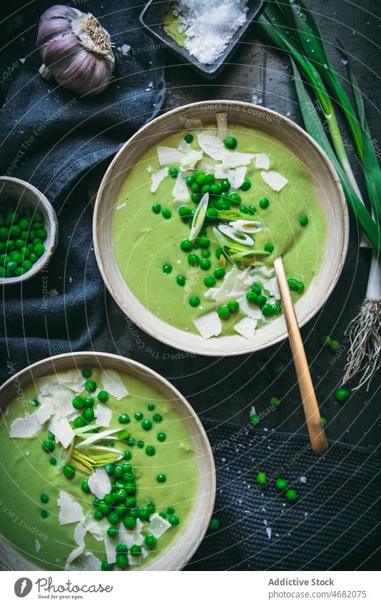 Erbsencreme auf dunklem Tisch Sahne Suppe kulinarisch Gastronomie Küche Püree Mahlzeit gesunde Ernährung Lebensmittel grün Zwiebel Löffel Serviette dienen