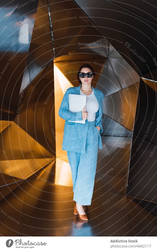 Frau mit Laptop in futuristischem Studio Atelier Mode modern Outfit Design 3d Stil kreativ feminin geometrisch Apparatur Gerät elegant Wand Dame trendy