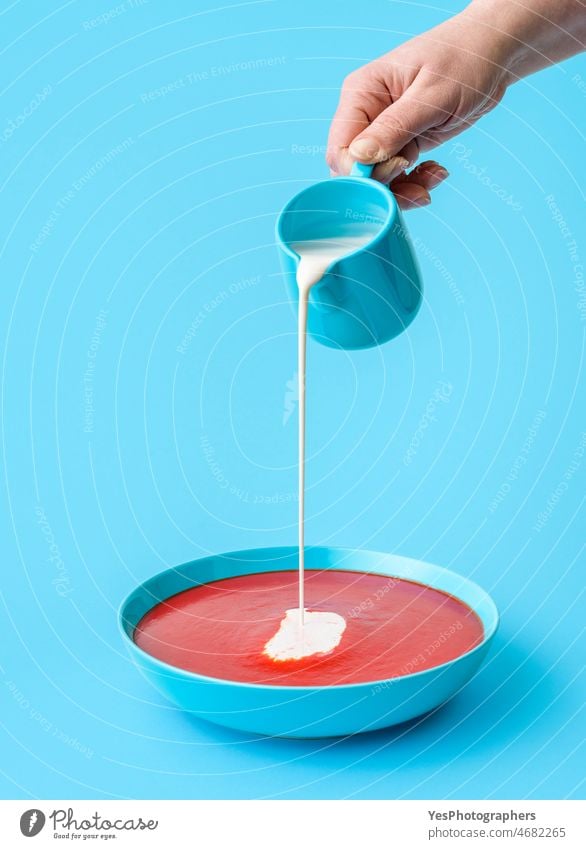 Gießen Sahne in Tomatensuppe minimalistisch auf einem blauen Hintergrund Schalen & Schüsseln Nahaufnahme Farbe Textfreiraum Küche lecker Abendessen Tropf