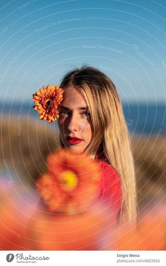 Künstlerisches Porträt einer kaukasischen Frau mit orangefarbenen Blumen und blauem Himmel Fotokunst Junge Frau Model im Freien hübsch niedlich lange Haare
