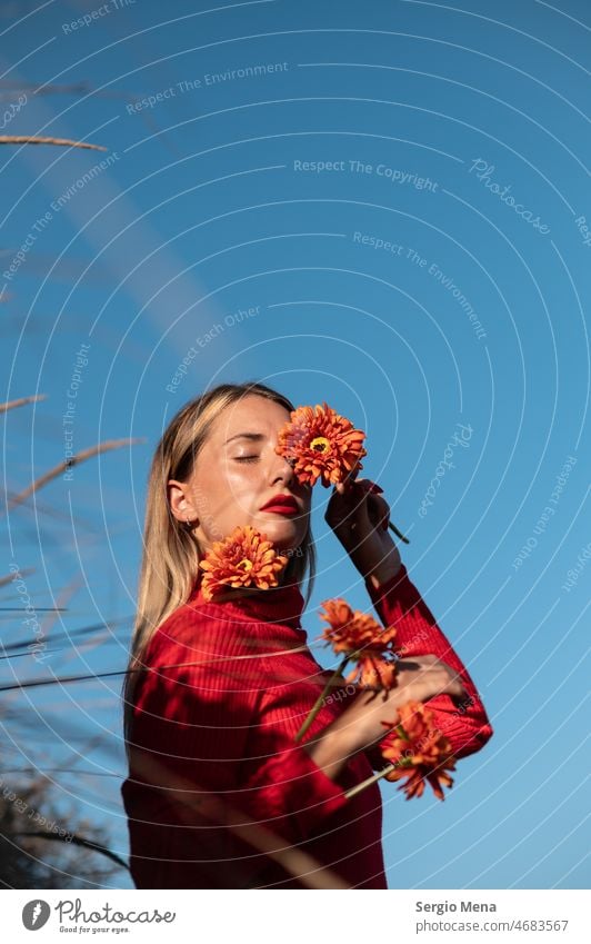Künstlerisches Porträt einer kaukasischen Frau mit orangefarbenen Blumen und blauem Himmel Fotokunst Model Junge Frau lange Haare niedlich hübsch im Freien