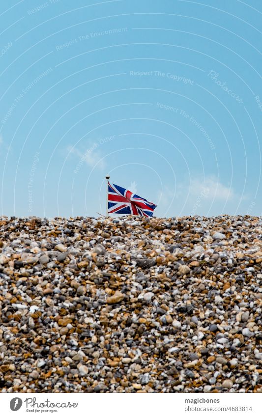 Die Flagge des Union Jack weht über einem Kieselsteinstrand oben Hintergrund Strand blau brexit britannien Briten Küste Küstenstreifen Tag Ost-Witterung England