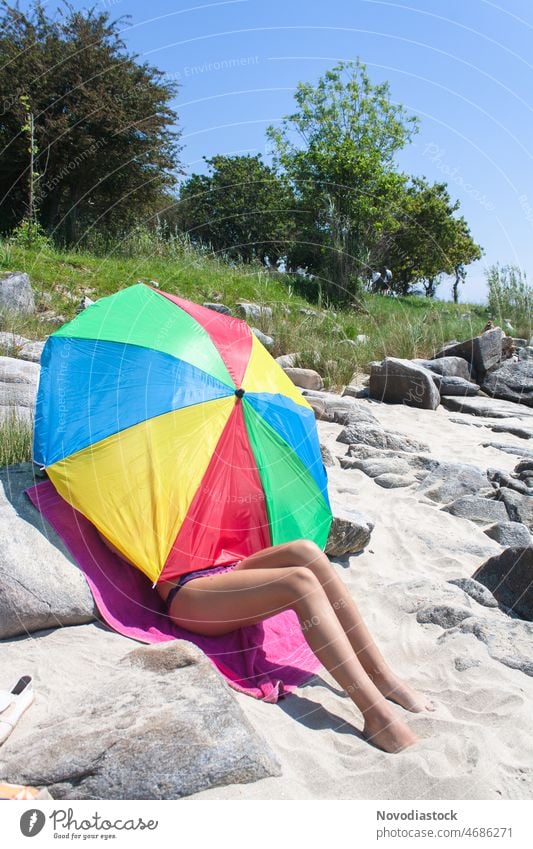 Teenager-Mädchen am Strand, bedeckt von einem Sonnenschirm, nur die Beine sind zu sehen Regenschirm Porträt sonnig außerhalb Sommer Ferien & Urlaub & Reisen