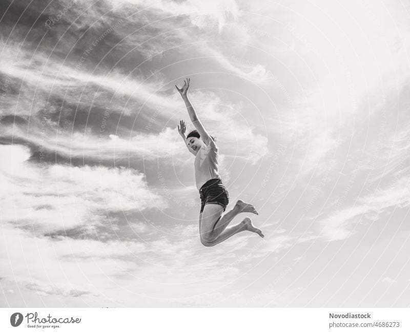 Schwarz-Weiß-Bild von einem Teenager-Mädchen springt hoch, isoliert, Himmel ist der Hintergrund springen schwarz auf weiß Schwarz-Weiß-Fotografie