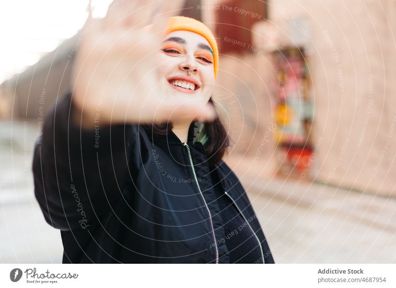 Fröhliche Frau zeigt Stopp-Geste in der Stadt stoppen Zeichen gestikulieren Stil informell Straße Großstadt trendy Design Gebäude Sonnenlicht Dame jung Mode