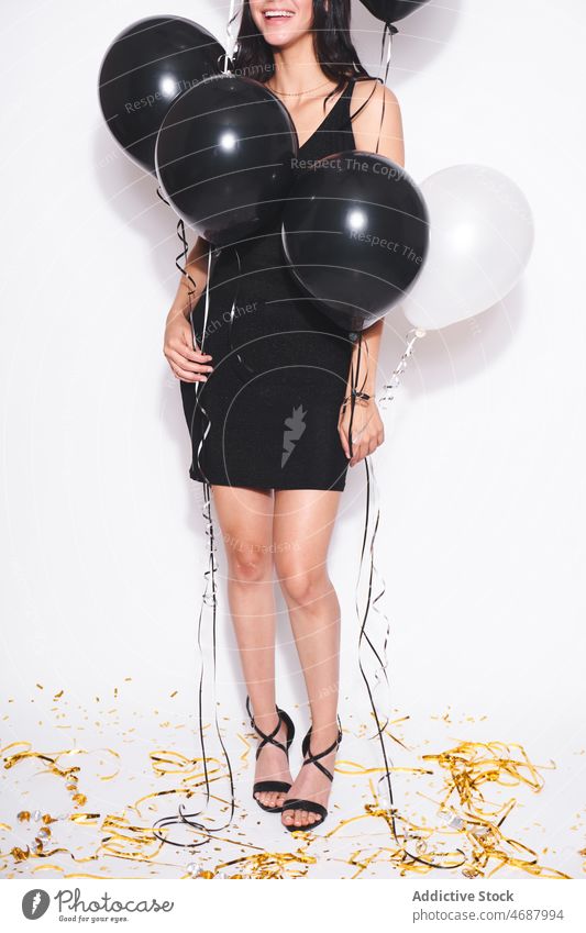 Anonyme attraktive Frau mit schwarzen und weißen Luftballons Geburtstag feiern Feiertag Stil Veranstaltung festlich Lächeln Mode schwarzes Kleid feminin