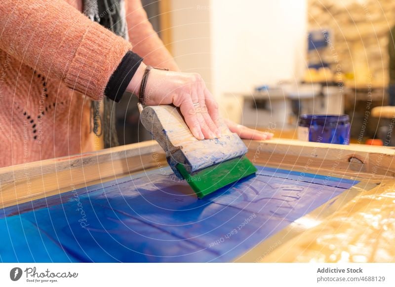 Handwerkerin schmiert mit einem Werkzeug Farbe auf ein Holzbrett Frau Tischlerin Presse drucken Prozess Bildschirm Werkstatt Basteln kreieren Holzarbeiten