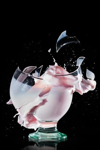 Glasbecher bricht und verschüttet seinen Inhalt. Hochgeschwindigkeitsfotografie auf schwarzem Hintergrund Brechen Unfug melken platschen trinken weiß Brille