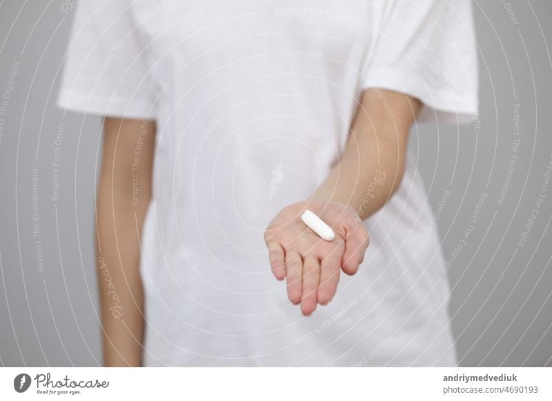 Frau in weißem T-Shirt, hält einen sauberen Tampon in den Händen, Nahaufnahme. weibliche Hygieneprodukte, Menstruation Beteiligung Schutz Zeitraum Hand Mädchen
