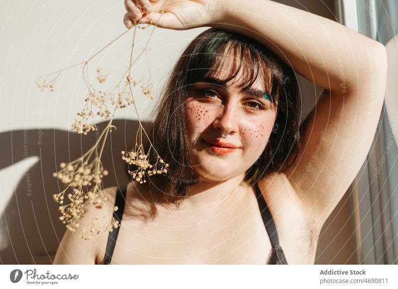 Übergewichtige Frau in Unterwäsche mit Trockenblumen Übergröße getrocknet Zweig Blume Figur Sonnenlicht Lächeln Dessous Raum genießen feminin Fenster Freude