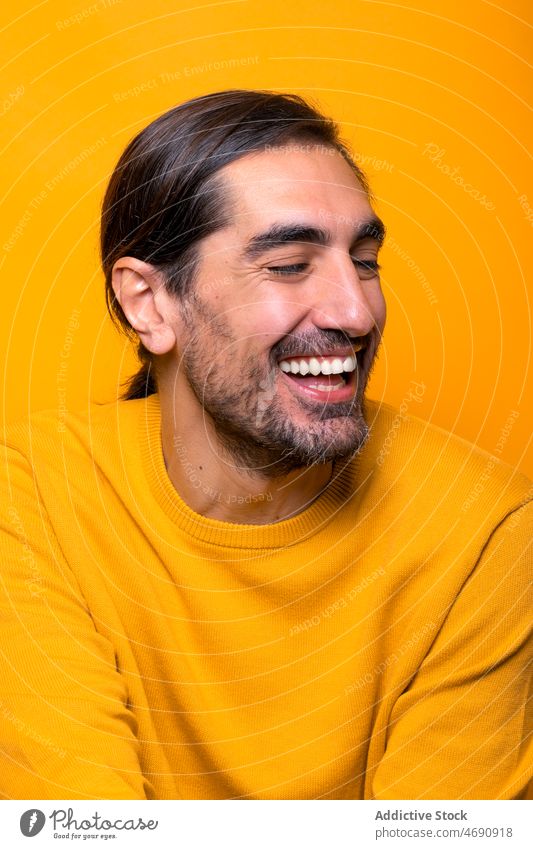 Fröhlicher Mann, der in einem gelben Studio wegschaut sorgenfrei lustig Vorschein Spaß Dummerchen Stimmung spielerisch Vollbart Porträt zeigen männlich