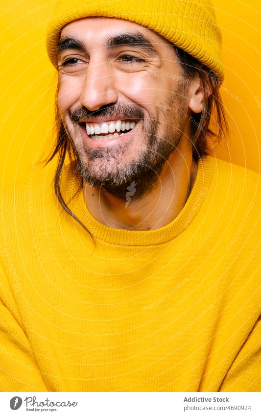 Fröhlicher Mann, der in einem gelben Studio wegschaut sorgenfrei lustig Vorschein Spaß Dummerchen Stimmung spielerisch Vollbart Porträt zeigen männlich