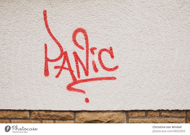 PANIC steht in roter Farbe auf der weiß gestrichenen Fassade Panic Panik Hauswand Putzfassade Zeichen Wand Angst Graffito Graffiti Schmiererei Schriftzeichen