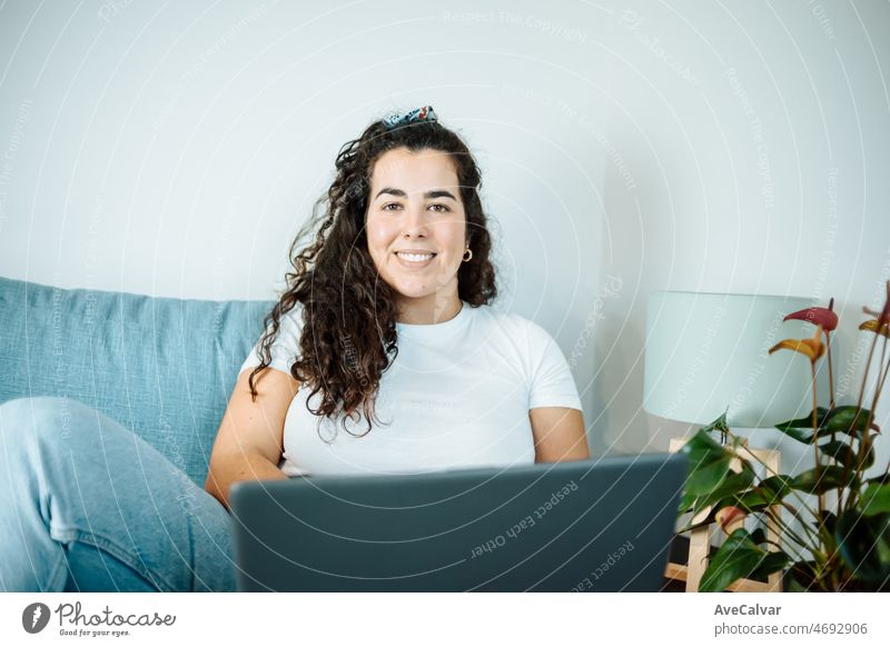Happy plus size lockige junge Frau lächelnd in die Kamera, während mit einem Laptop vorzubereiten, und tun Arbeit online zu Hause, Remote-Tasking. Moderne Stadtwohnung. Die Rechnungen werden bezahlt. Unternehmerin Freiberuflerin Frauen