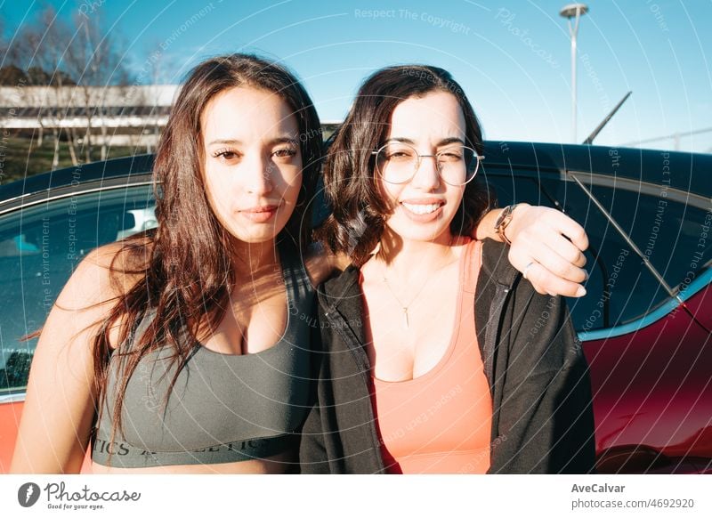 Zwei junge sportliche Frau Freunde ernst in die Kamera vor dem Eintritt in die Turnhalle, gegen Auto ruht. Training Gewicht verlieren mit Freunden zusammen lächelnd in die Kamera glücklich. Freundschaft zwischen Schwestern Konzept