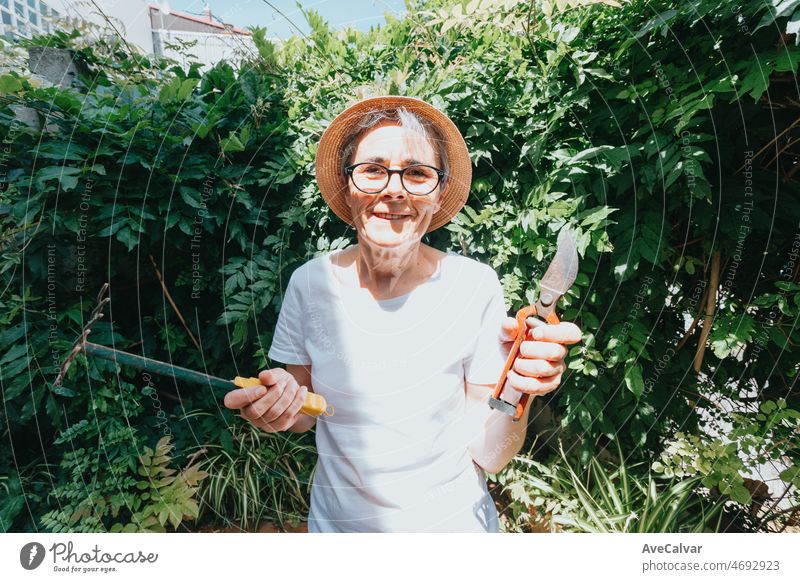 Porträt einer alten Frau, die Gartengeräte hält und in die Kamera lächelt. Freizeitbeschäftigung zu Hause. Rettet den Planeten, indem er Pflanzen pflanzt. Planet betrifft. Reife Menschen arbeitet zu Hause
