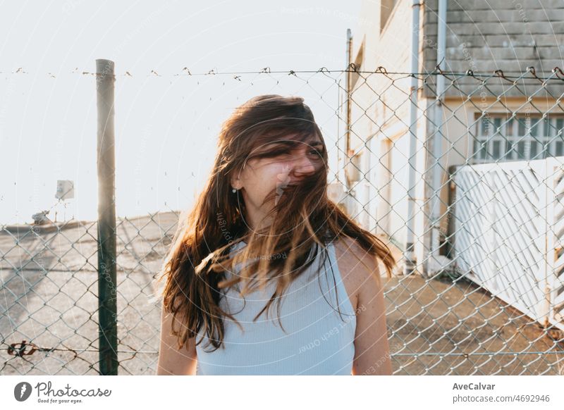 Frontalporträt einer jungen Frau mit langen Haaren, die während des Sonnenuntergangs mit den Haaren wedelt, Gesicht mit Haaren bedeckt. Freiheit, Freiheit und Zukunft ist junges Konzept. Outdoors Lifestyle auf sozialem Netzwerk. trendy gen z.