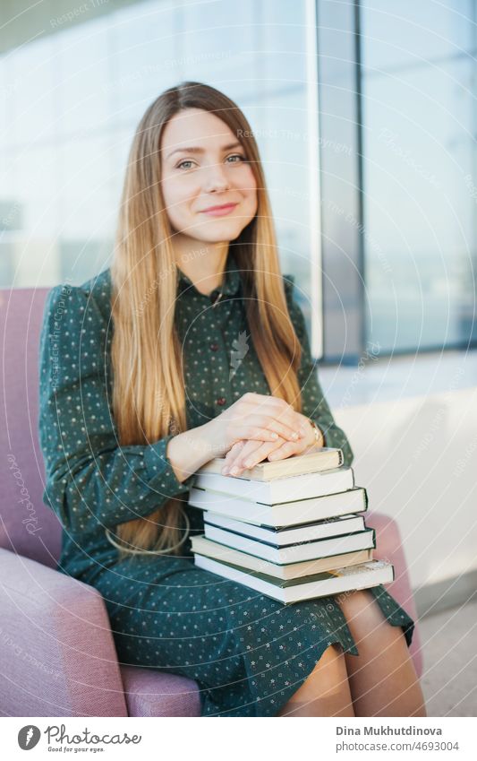 Junge schöne Frau in grünem Kleid hält einen Stapel Bücher. Studentin mit Büchern zum Lernen. Bildung und Wissen. Millennial Lebensstil. Universitätsbibliothek oder Buchhandlung. Bücherwurm.