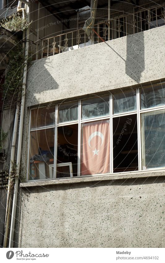 Vergilbte rote türkische Fahne im Fenster eines heruntergekommenen Büro im Sommer bei Sonnenschein in den Gassen der Altstadt von Taksim an der Istiklal Caddesi im Stadtteil Beyoglu in Istanbul am Bosporus in der Türkei