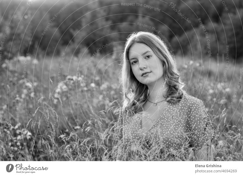 Ein junges, schönes Mädchen steht auf einem Feld. Konzept der Entschleunigung und Nähe zur Natur Porträt Gras Blumen Sommer Sonne schwarz auf weiß Behaarung